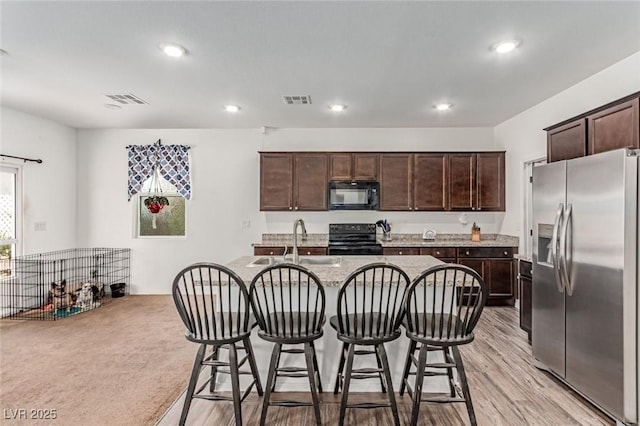 3821 E Summit Ave, Pahrump, NV 89061 - kitchen featuring black appliances, a sink, dark brown cabinets, a breakfast bar area, and a center island with sink