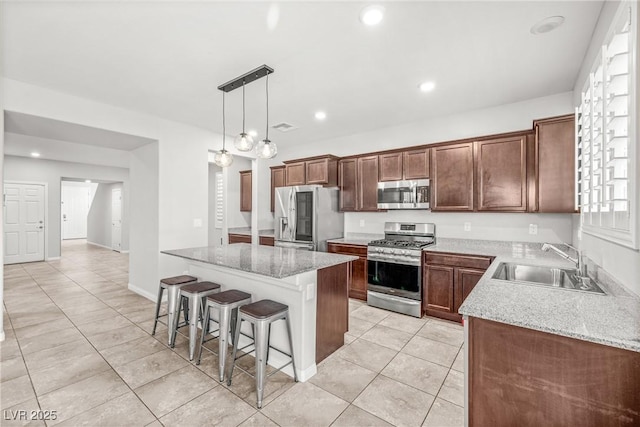 4519 Stardusk Falls Ave, North Las Vegas, NV 89084 - kitchen featuring stainless steel appliances, a sink, a center island, light tile patterned flooring, and a breakfast bar