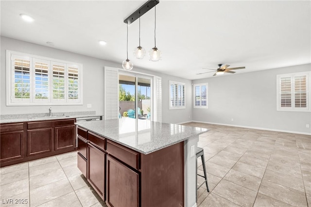 4519 Stardusk Falls Ave, North Las Vegas, NV 89084 - kitchen with light tile patterned floors, a sink, a ceiling fan, a breakfast bar, and light stone counters