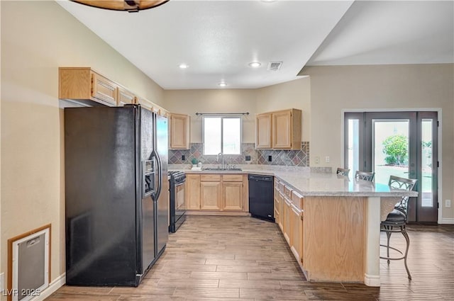 983 Cutter St, Henderson, NV 89011 - kitchen with black appliances, light brown cabinets, a peninsula, a kitchen breakfast bar, and light countertops