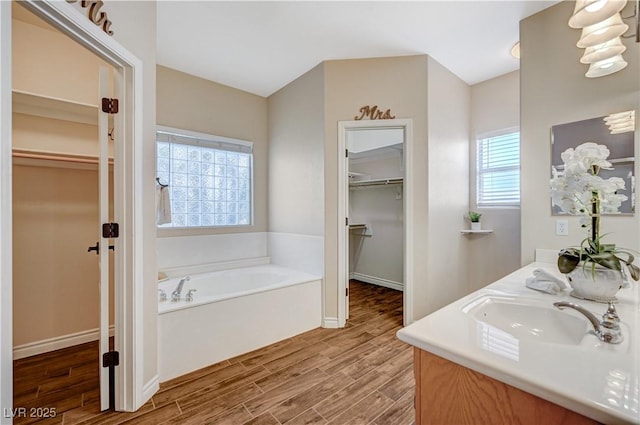 983 Cutter St, Henderson, NV 89011 - full bathroom featuring a walk in closet, a bath, wood finished floors, and double vanity