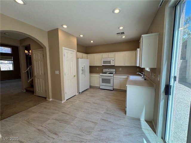 5861 Varese Dr, Las Vegas, NV 89141 - kitchen with white appliances, a sink, arched walkways, light countertops, and white cabinetry