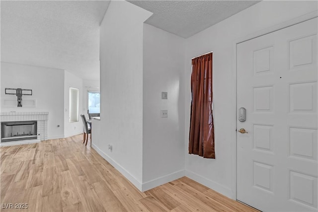 765 Butternut Ct, Henderson, NV 89014 - foyer entrance with a textured ceiling, light wood finished floors, baseboards, and a brick fireplace