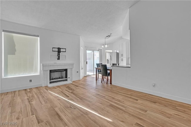 765 Butternut Ct, Henderson, NV 89014 - unfurnished living room with light wood finished floors, a fireplace, a textured ceiling, a chandelier, and baseboards