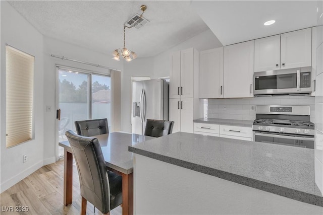 765 Butternut Ct, Henderson, NV 89014 - kitchen with stainless steel appliances, a chandelier, white cabinets, backsplash, and light wood-style flooring