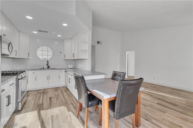 765 Butternut Ct, Henderson, NV 89014 - kitchen featuring stainless steel appliances, a sink, light wood finished floors, white cabinetry, and recessed lighting