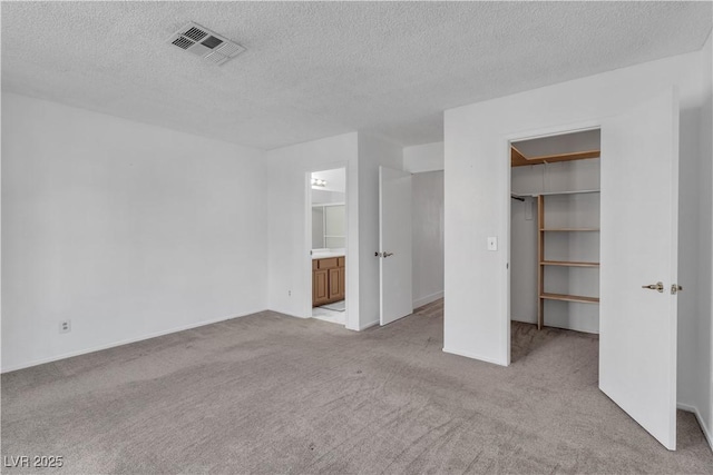 765 Butternut Ct, Henderson, NV 89014 - unfurnished bedroom featuring light carpet, a walk in closet, a textured ceiling, a closet, and attic access