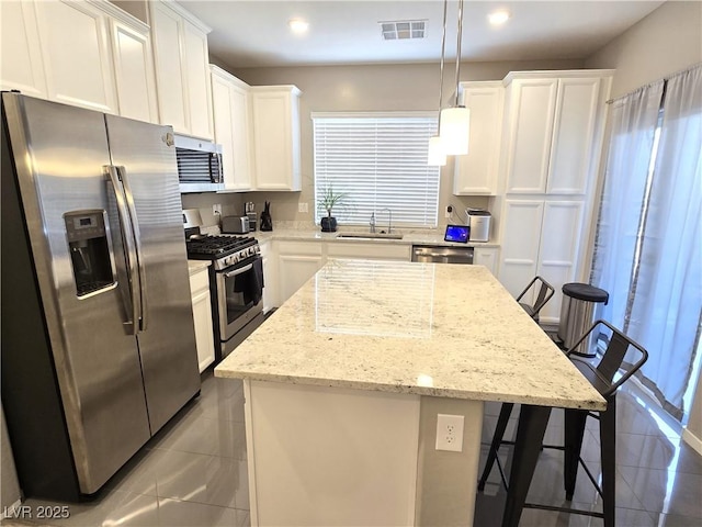 8534 Insignia Ave Unit 101, Las Vegas, NV 89178 - kitchen featuring stainless steel appliances, white cabinetry, a kitchen breakfast bar, a center island, and hanging light fixtures