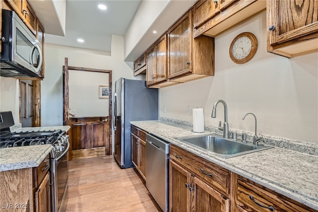 4075 E Oquendo Rd, Las Vegas, NV 89120 - kitchen with appliances with stainless steel finishes, a sink, light wood-style floors, brown cabinetry, and recessed lighting