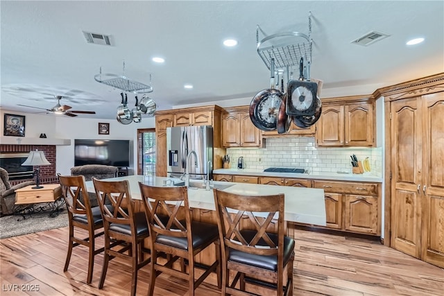 4075 E Oquendo Rd, Las Vegas, NV 89120 - kitchen with stainless steel fridge, gas stovetop, light wood finished floors, a kitchen bar, and light countertops