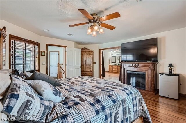 4075 E Oquendo Rd, Las Vegas, NV 89120 - bedroom with light wood-type flooring, refrigerator, ceiling fan, a glass covered fireplace, and ensuite bath