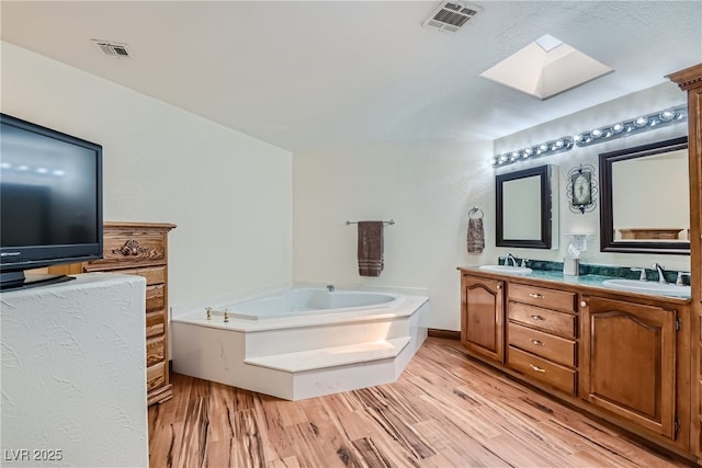 4075 E Oquendo Rd, Las Vegas, NV 89120 - full bathroom featuring a skylight, double vanity, a bath, and wood finished floors