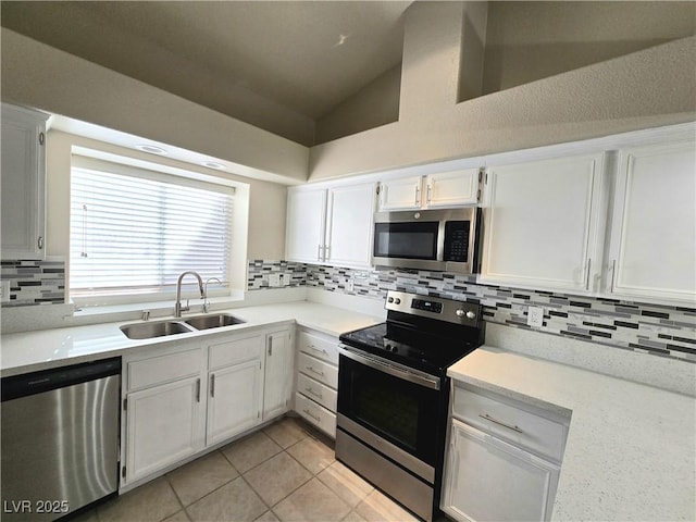 2035 E Warm Springs Rd Unit 1017, Las Vegas, NV 89119 - kitchen with appliances with stainless steel finishes, a sink, white cabinetry, backsplash, and lofted ceiling