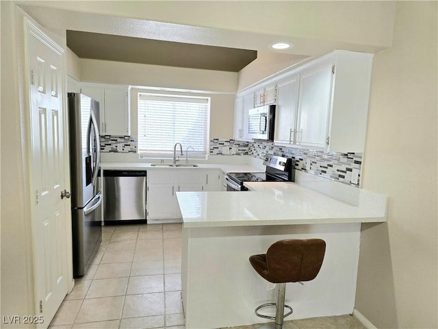2035 E Warm Springs Rd Unit 1017, Las Vegas, NV 89119 - kitchen featuring appliances with stainless steel finishes, a sink, a peninsula, backsplash, and light countertops