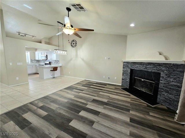 2035 E Warm Springs Rd Unit 1017, Las Vegas, NV 89119 - unfurnished living room featuring ceiling fan, a glass covered fireplace, baseboards, light wood finished floors, and lofted ceiling