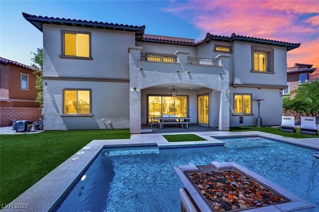 362 Port Reggio St, Las Vegas, NV 89138 - back of property featuring a balcony, a lawn, stucco siding, a patio area, and an outdoor pool