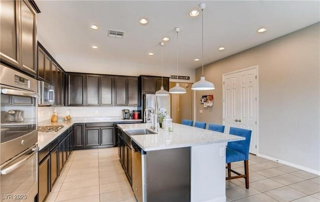 10262 Havasu Falls St, Las Vegas, NV 89141 - kitchen with a sink, stainless steel appliances, light tile patterned floors, a kitchen bar, and dark brown cabinetry