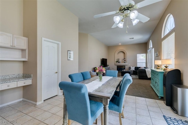 2090 Eaglepath Cir, Henderson, NV 89074 - dining room with light tile patterned floors, ceiling fan, a glass covered fireplace, baseboards, and light carpet