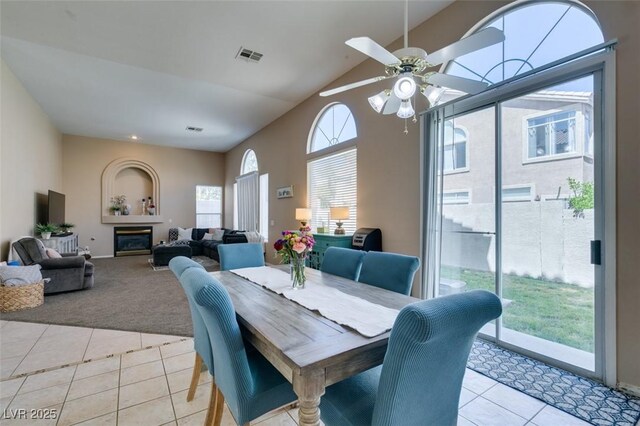 2090 Eaglepath Cir, Henderson, NV 89074 - dining room with light tile patterned floors, light colored carpet, ceiling fan, high vaulted ceiling, and a glass covered fireplace