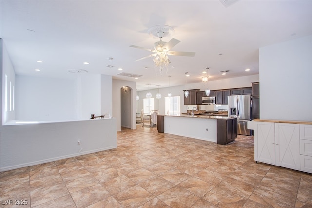1794 Morro Vista Dr, Las Vegas, NV 89135 - kitchen featuring stainless steel appliances, ceiling fan, a sink, dark brown cabinetry, and a center island with sink
