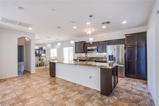 1794 Morro Vista Dr, Las Vegas, NV 89135 - kitchen featuring appliances with stainless steel finishes, dark brown cabinetry, arched walkways, a sink, and light stone counters