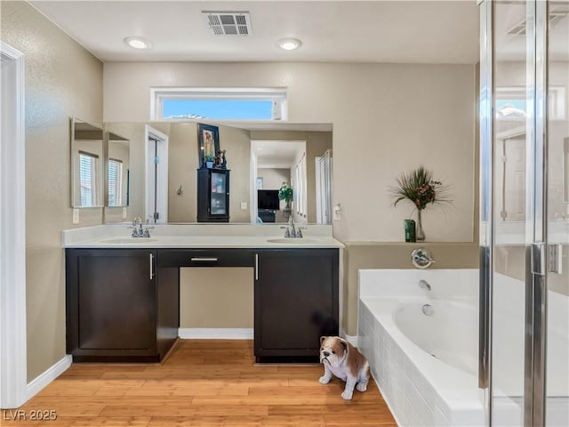 8754 Brindisi Park Ave, Las Vegas, NV 89148 - full bath with double vanity, a garden tub, and wood finished floors