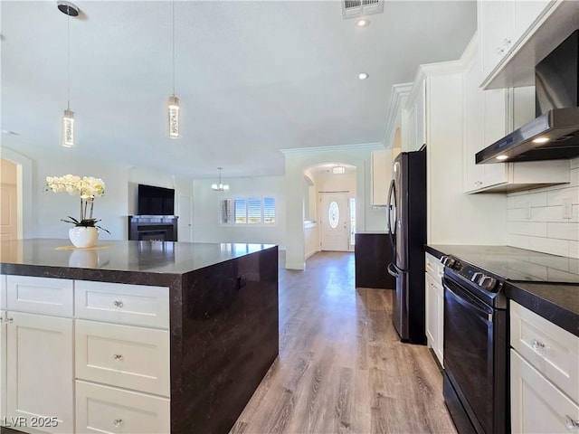 5500 Santovito St, Pahrump, NV 89061 - kitchen with black range with electric cooktop, range hood, freestanding refrigerator, arched walkways, and white cabinets