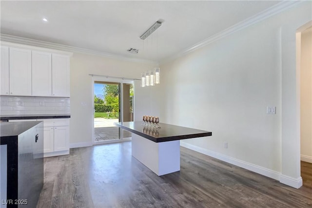 5500 Santovito St, Pahrump, NV 89061 - kitchen with baseboards, dark countertops, crown molding, dark wood finished floors, and white cabinetry