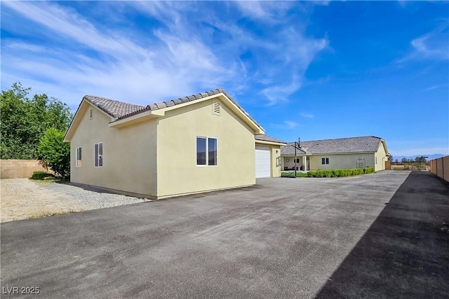 5500 Santovito St, Pahrump, NV 89061 - view of property exterior with a garage, a tile roof, asphalt driveway, and stucco siding