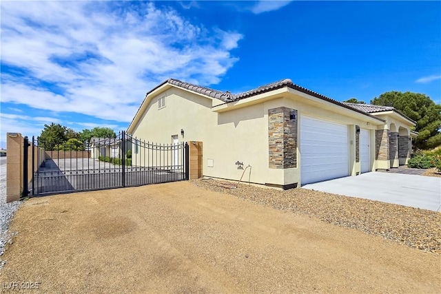 5500 Santovito St, Pahrump, NV 89061 - view of home's exterior featuring concrete driveway, a gate, stone siding, stucco siding, and an attached garage