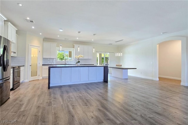 5500 Santovito St, Pahrump, NV 89061 - kitchen with black range with electric cooktop, arched walkways, a center island with sink, ornamental molding, and backsplash