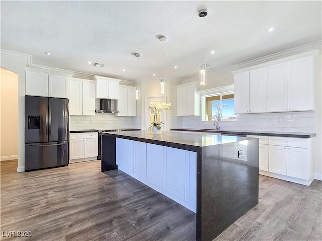 5500 Santovito St, Pahrump, NV 89061 - kitchen with stainless steel refrigerator with ice dispenser, wall chimney exhaust hood, dark countertops, a sink, and a center island
