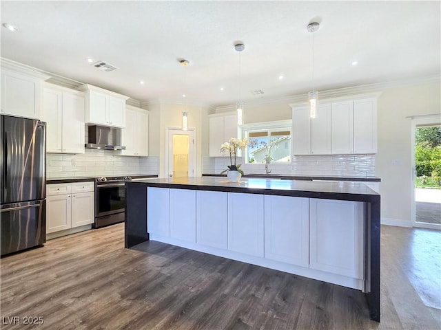 5500 Santovito St, Pahrump, NV 89061 - kitchen with appliances with stainless steel finishes, dark countertops, wall chimney range hood, dark wood-style flooring, and ornamental molding