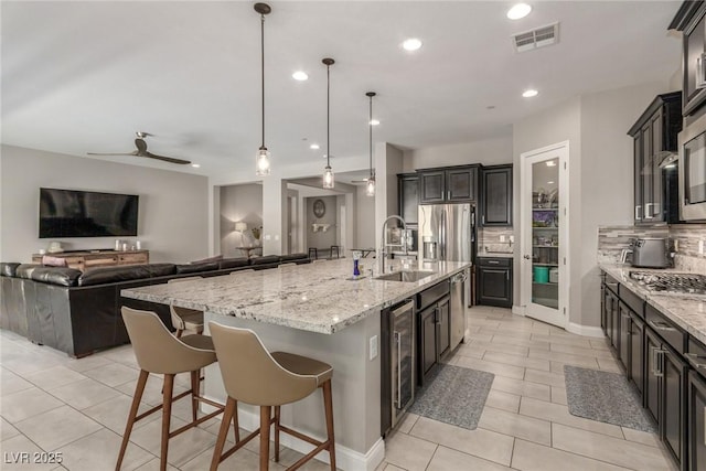 8 Via Tiberina, Las Vegas, NV 89011 - kitchen featuring wine cooler, a sink, light tile patterned floors, light stone countertops, and a large island with sink