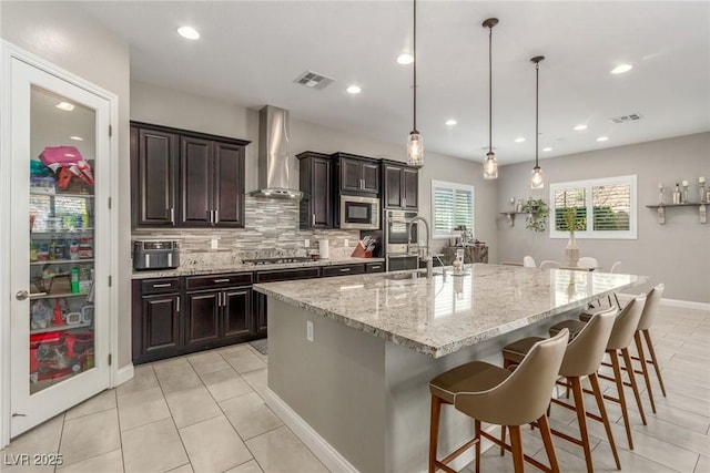 8 Via Tiberina, Las Vegas, NV 89011 - kitchen featuring wall chimney exhaust hood, stainless steel appliances, a kitchen bar, an island with sink, and tasteful backsplash