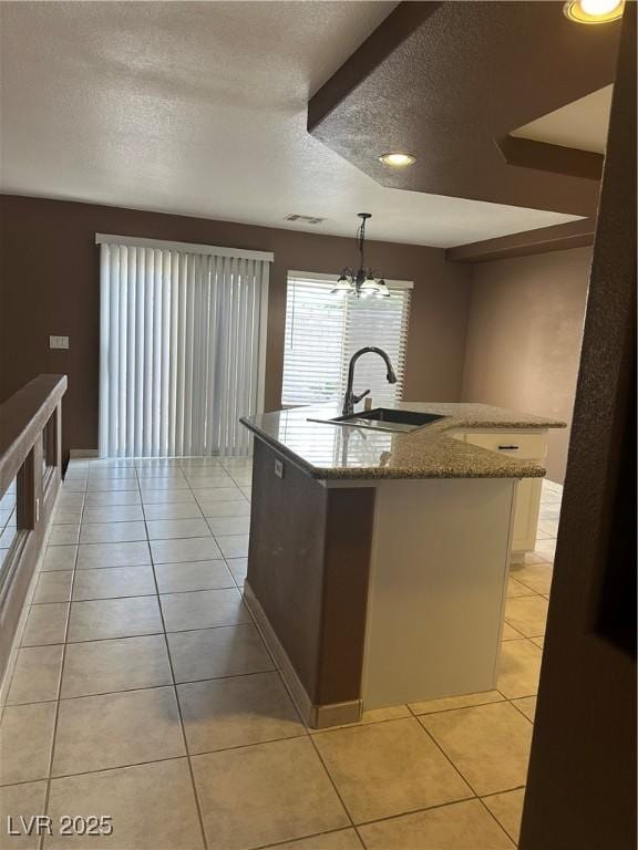 1511 Balsam Mist Ave, Las Vegas, NV 89183 - kitchen with a sink, a textured ceiling, light tile patterned flooring, stone countertops, and a center island with sink
