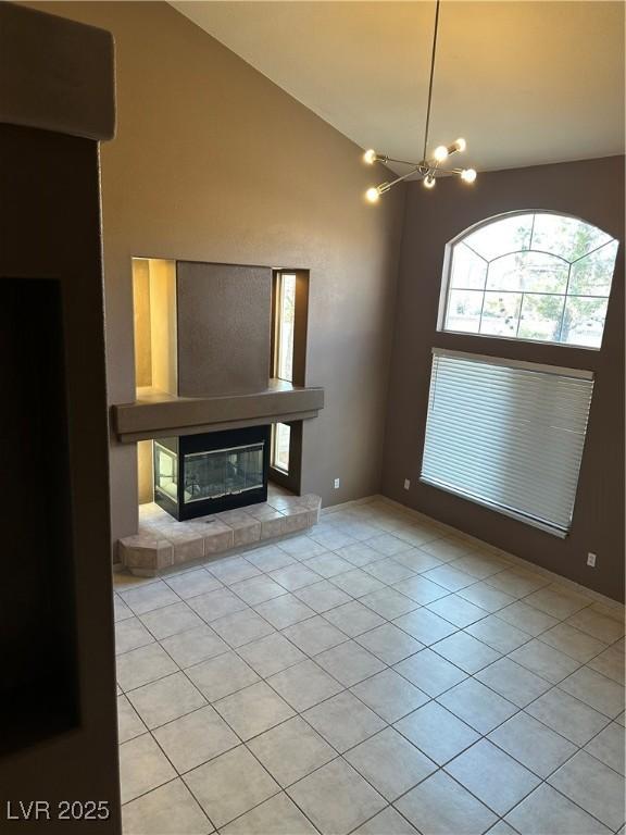 1511 Balsam Mist Ave, Las Vegas, NV 89183 - unfurnished living room featuring high vaulted ceiling, light tile patterned flooring, a tiled fireplace, a chandelier, and baseboards