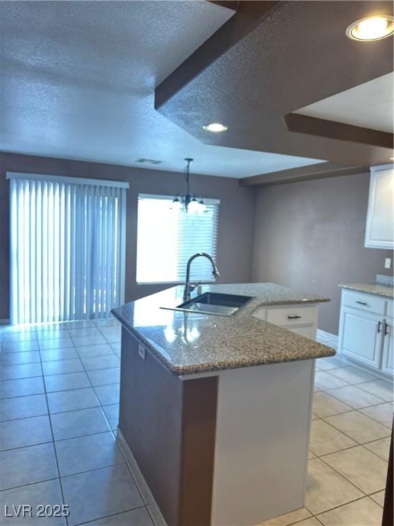 1511 Balsam Mist Ave, Las Vegas, NV 89183 - kitchen with a sink, a textured ceiling, light tile patterned flooring, healthy amount of natural light, and white cabinets