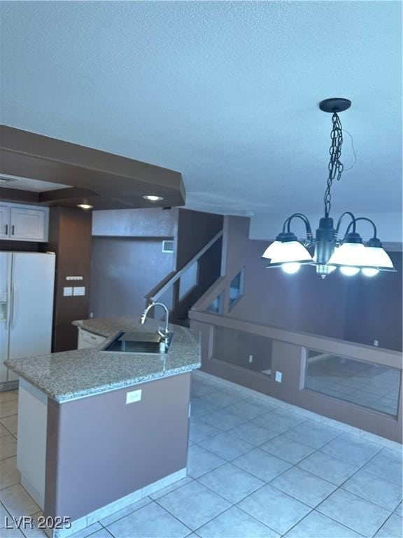 1511 Balsam Mist Ave, Las Vegas, NV 89183 - kitchen with white refrigerator with ice dispenser, a sink, a kitchen island with sink, a chandelier, and light tile patterned floors
