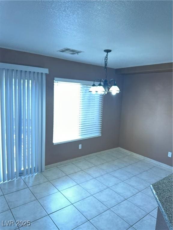 1511 Balsam Mist Ave, Las Vegas, NV 89183 - unfurnished room featuring a chandelier, a textured ceiling, light tile patterned floors, and baseboards