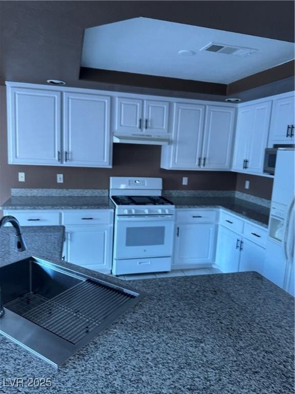 1511 Balsam Mist Ave, Las Vegas, NV 89183 - kitchen with gas range gas stove, under cabinet range hood, white cabinetry, a sink, and dark stone countertops