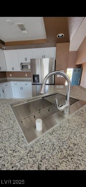 1511 Balsam Mist Ave, Las Vegas, NV 89183 - kitchen with stainless steel appliances, white cabinets, a sink, and light stone countertops