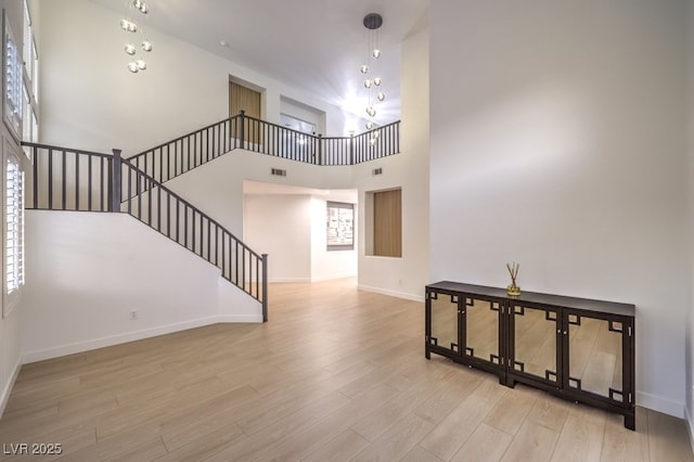 722 Descartes Ave, Henderson, NV 89002 - unfurnished living room featuring baseboards, wood finished floors, stairway, and a towering ceiling