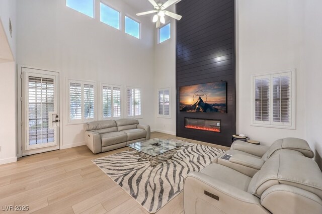 722 Descartes Ave, Henderson, NV 89002 - living area featuring a high ceiling, light wood-style flooring, ceiling fan, a fireplace, and baseboards