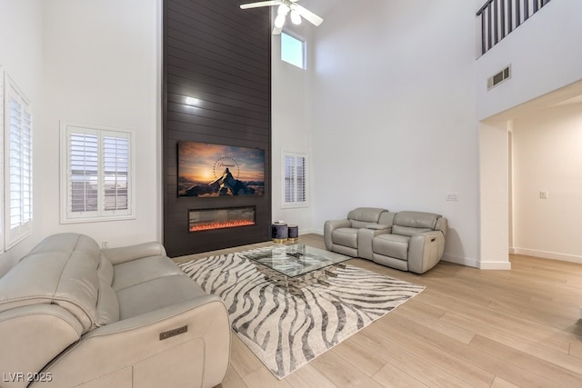 722 Descartes Ave, Henderson, NV 89002 - living area featuring a towering ceiling, a ceiling fan, wood finished floors, baseboards, and a large fireplace