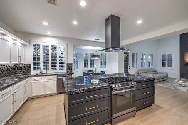 722 Descartes Ave, Henderson, NV 89002 - kitchen with appliances with stainless steel finishes, island exhaust hood, a sink, white cabinetry, and dark stone countertops