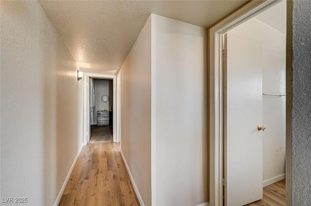 2496 Golfers St, Las Vegas, NV 89142 - corridor featuring light wood-type flooring, a textured ceiling, baseboards, and a textured wall