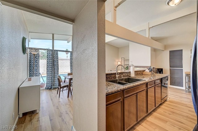 2496 Golfers St, Las Vegas, NV 89142 - kitchen with a textured wall, a sink, light wood finished floors, brown cabinetry, and dishwasher
