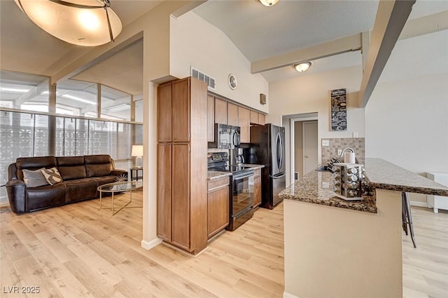 2496 Golfers St, Las Vegas, NV 89142 - kitchen featuring black appliances, tasteful backsplash, a kitchen breakfast bar, light wood-style floors, and vaulted ceiling