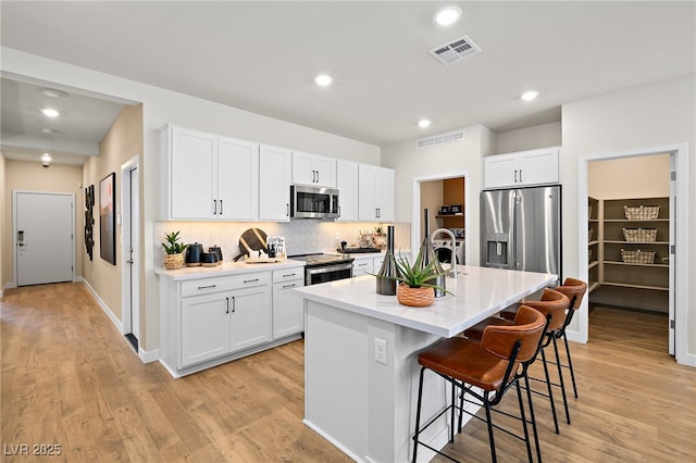 4130 E Brusca Way, Pahrump, NV 89061 - kitchen with stainless steel appliances, a kitchen bar, light wood-type flooring, tasteful backsplash, and recessed lighting
